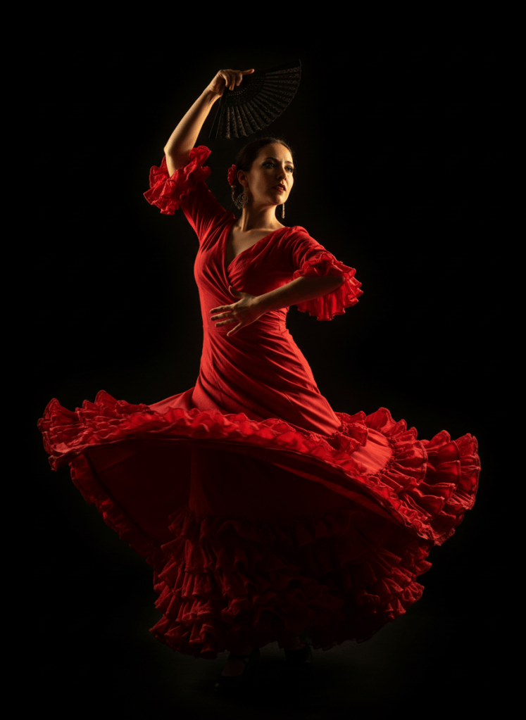 Dramatic portrait of a female flamenco dancer mid-movement, red ruffled dress swirling, black background, cinematic warm golden rim lighting, high contrast, elegant editorial photography